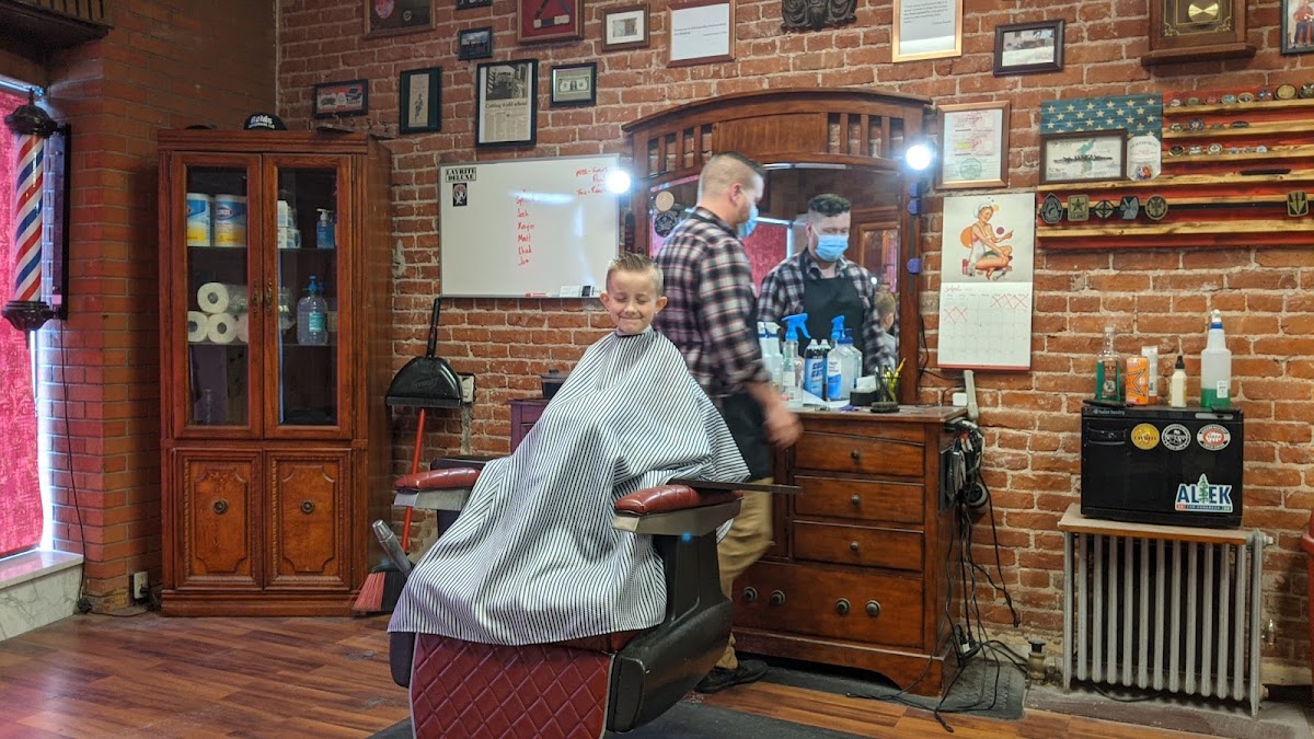 A young customer getting a haircut against the exposed-brick wall